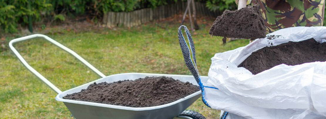 Shoveling soil from a bag to a wheelbarrow