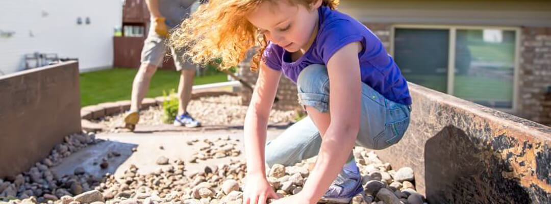 Little girl placing rocks in backyard