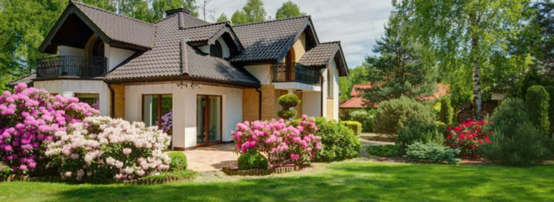 Big house with a yard full of pink and white flowers